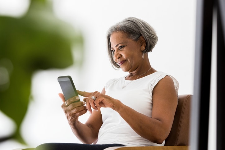 Lady with grey bobbed hair sitting down looking at phone