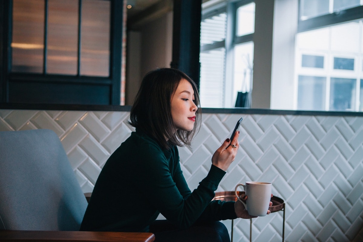 Lady looking at phone with coffee in hand