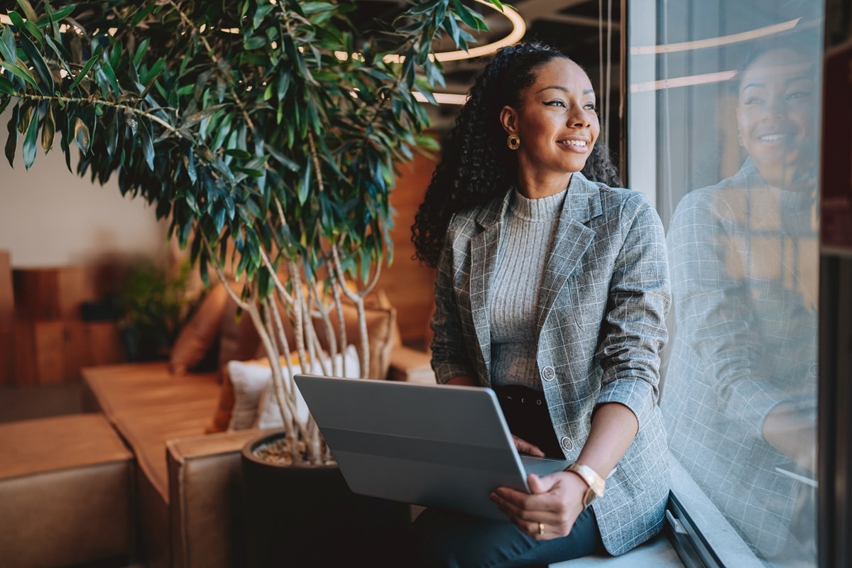 Lady in grey suit jacket sitting by window looking out