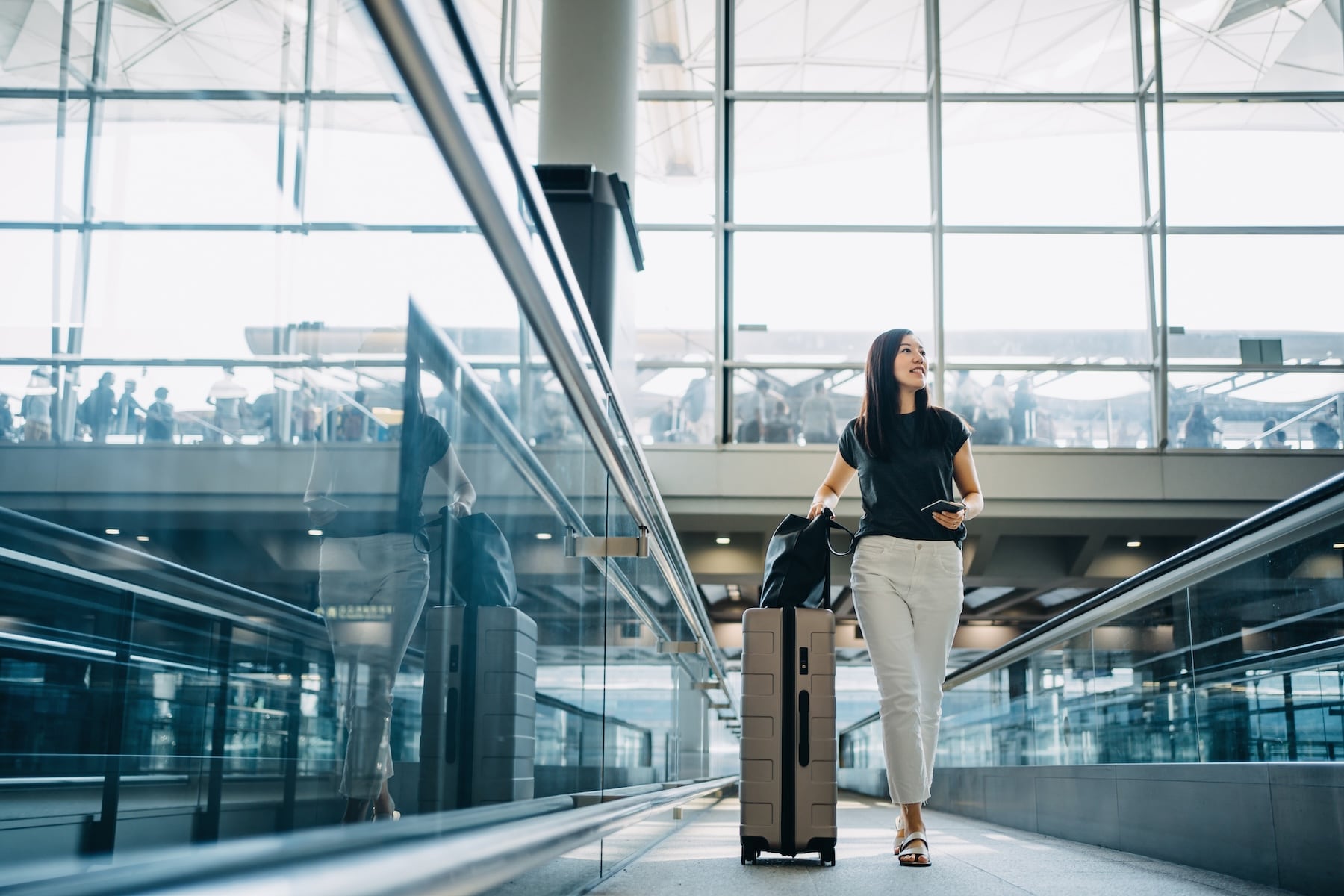 woman walking through airport with suitcase