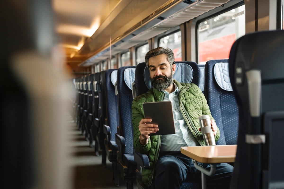 Man on train with coffee reading kindle 