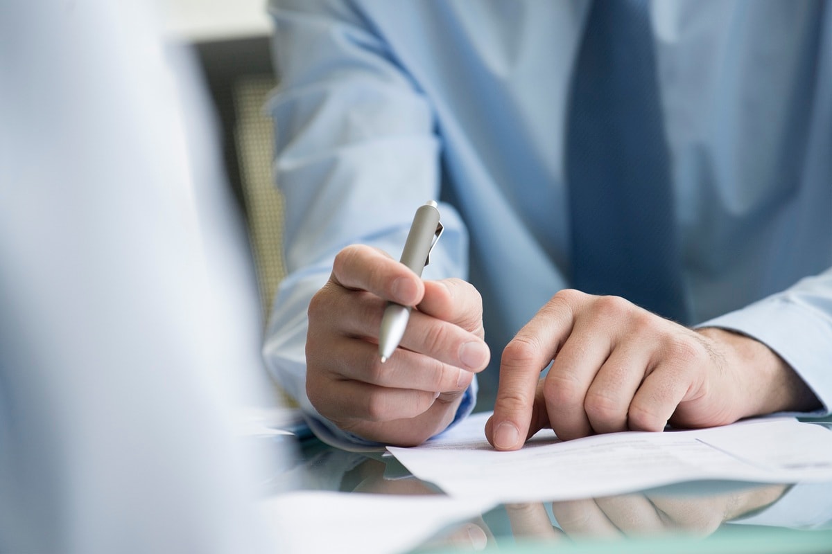 Male hands holding a pen, resting on paperwork