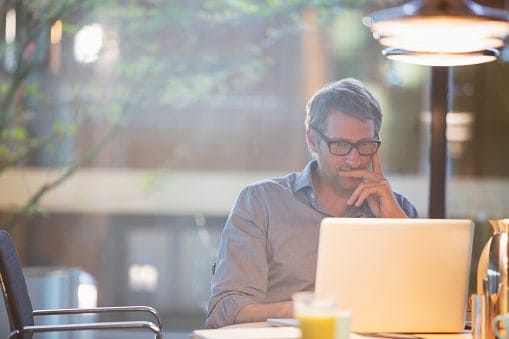 Man sitting behind laptop with sun shining 