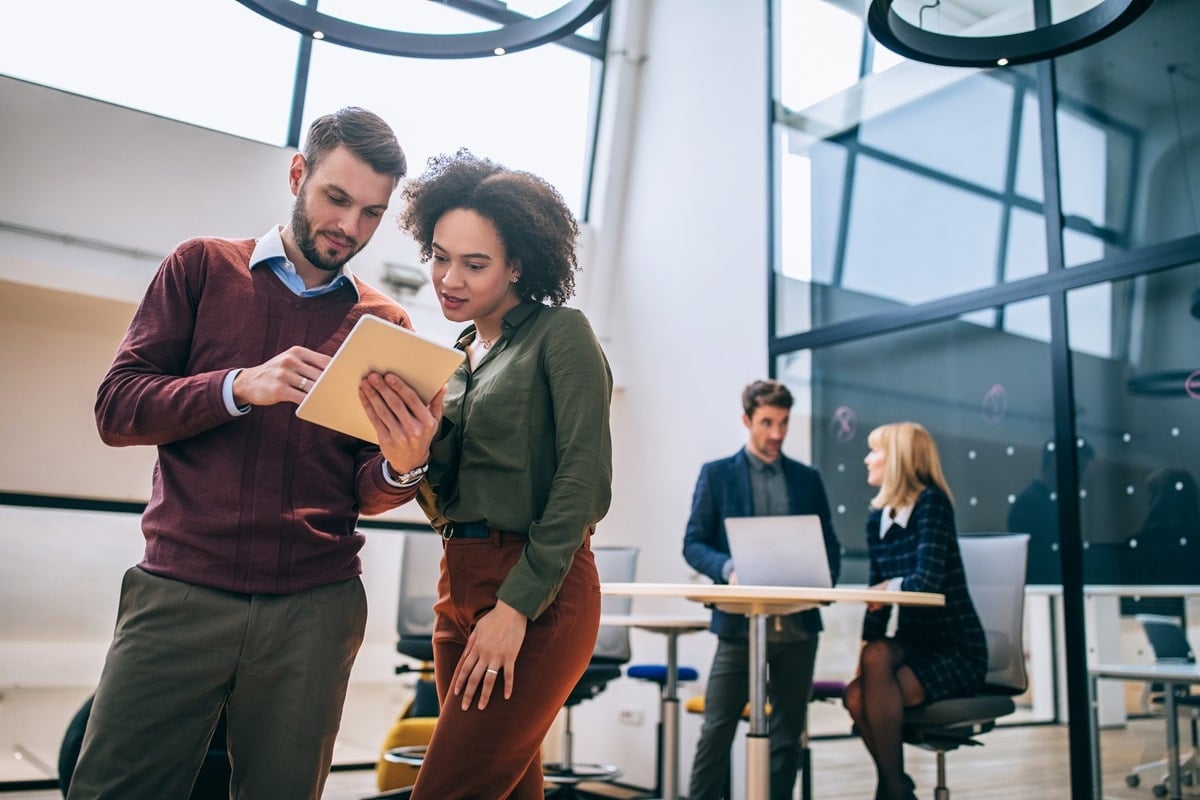 Man and women in office looking at tablet together