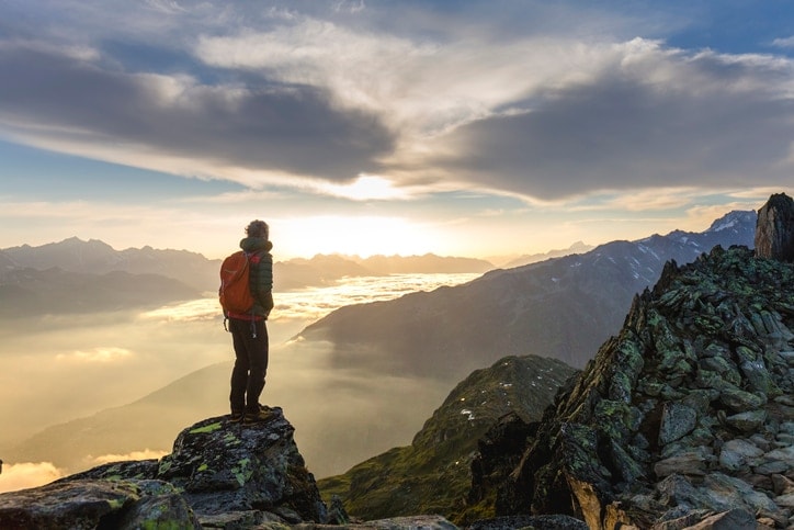 Man standing on top of mountain looking at sunrise