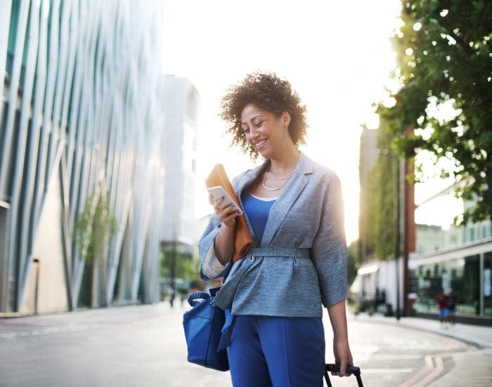 Lady in work attire on business trip stopped to look at phone