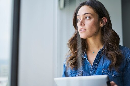 Lady with brown hair and blue shirt looking out of window