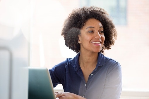 Lady in dark blue shirt looking away from her computer