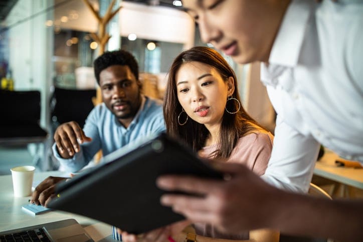 Three people looking at a tablet screen