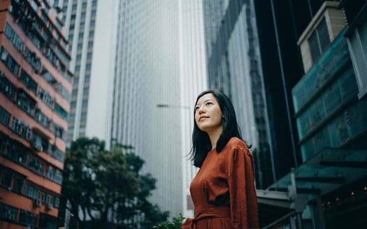 Lady with long black hair in brown dress standing on street outside office