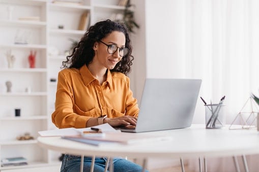 Lady sitting in white office looking at laptop 