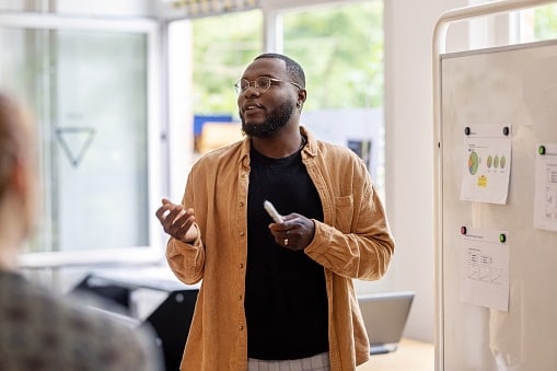 Man standing in front of whiteboard with chart print outs stuck to it