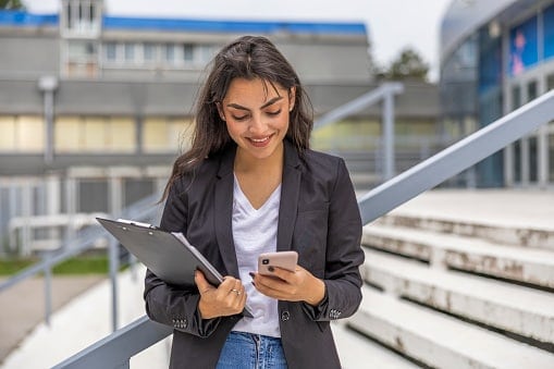 Lady with clipboard and phone outside building 