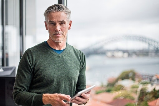 Man in green jumper standing in front of large window