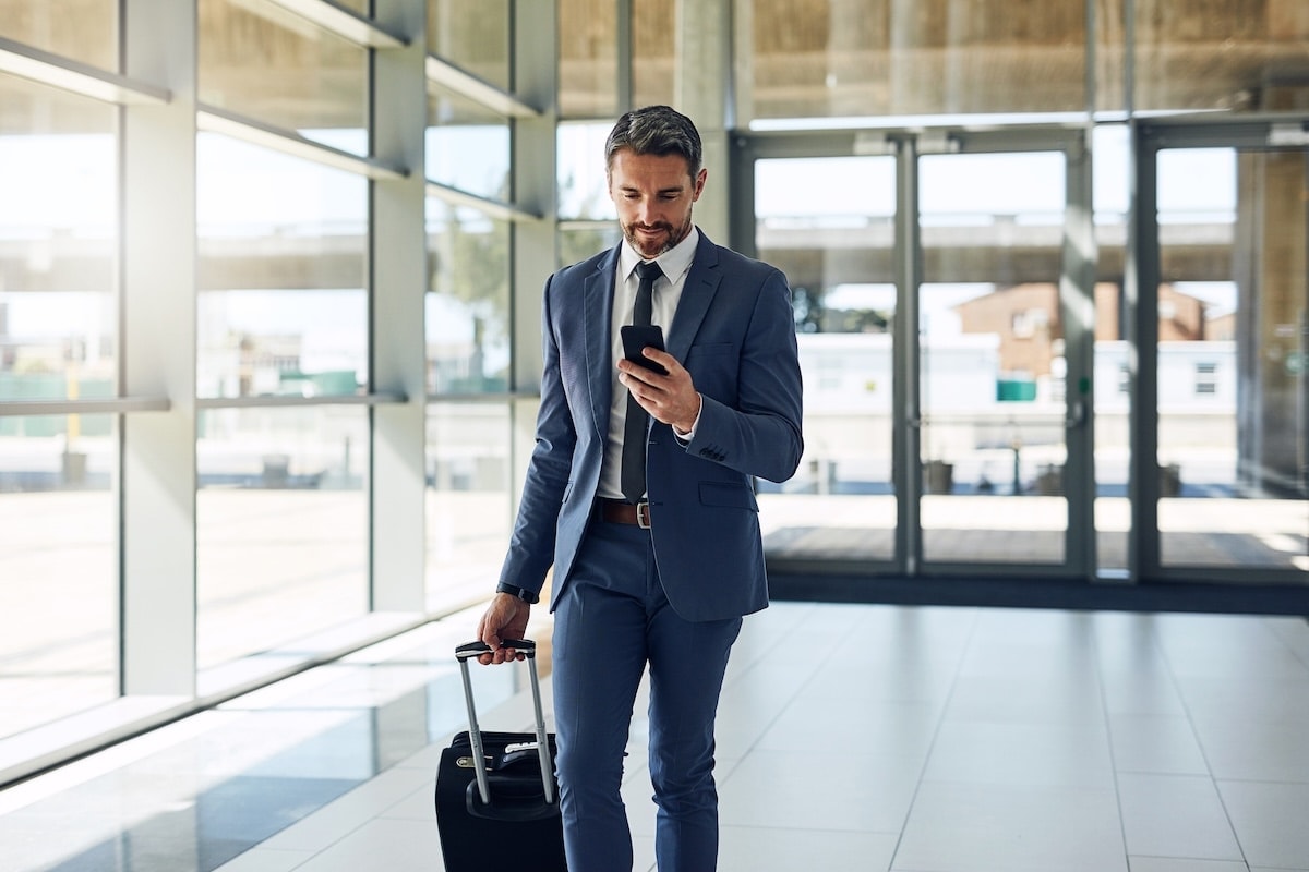 man holding phone and suitcase