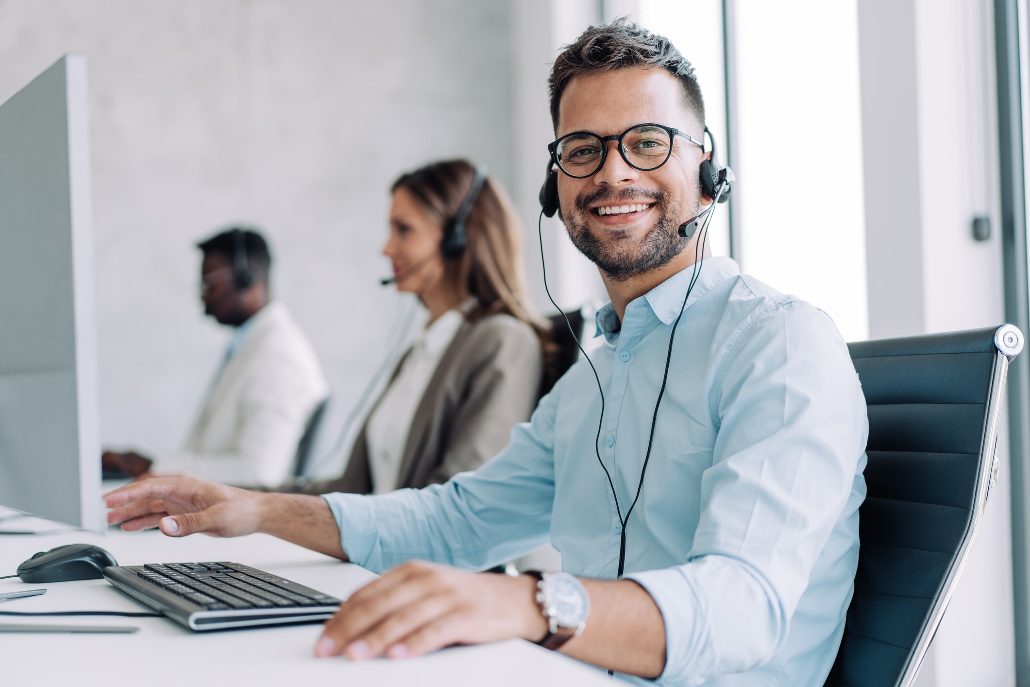 Man at computer with headset looking at camera