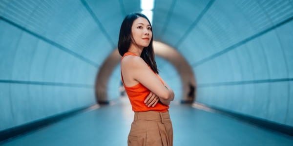 asian woman with crossed arms standing in futuristic tunnel
