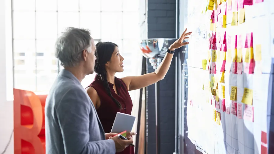 two people working on a whiteboard in office