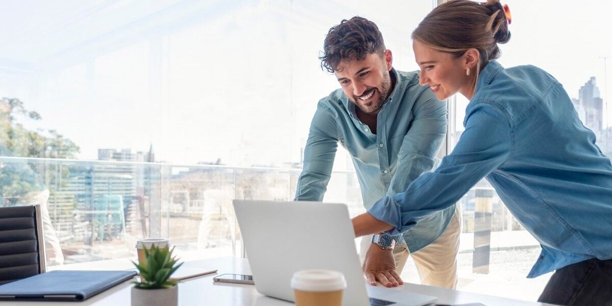 Two employees smiling at laptop