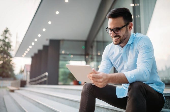 Man with tablet sitting outside office 